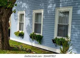 A light blue wooden horizontal clapboard covered house with a double hung pane window